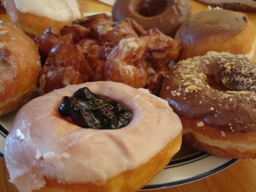 A plate of assorted donuts, including glazed, chocolate, and jelly-filled varieties, arranged appetizingly.