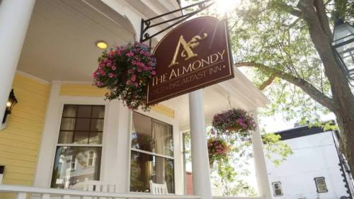 Sign for "The Almondy Bed & Breakfast Inn" with hanging flower baskets and a charming porch setting.