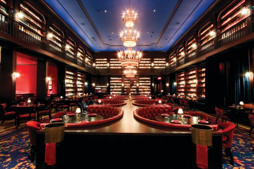 Elegant restaurant interior with red booths, chandeliers, and a blue ceiling, creating a luxurious atmosphere.