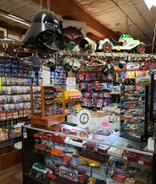A vintage toy store filled with collectibles, including a Darth Vader helmet and various model cars on display.