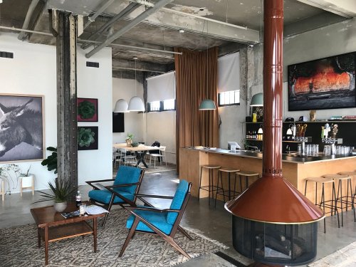 A modern cafe interior featuring a cozy seating area, bar, and artistic decor with a warm color palette.