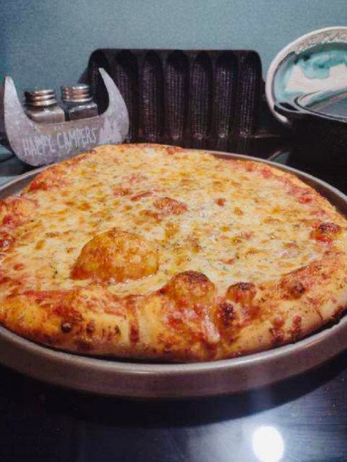 A freshly baked cheese pizza on a metal tray, with a golden crust and bubbling cheese, set on a dark countertop.