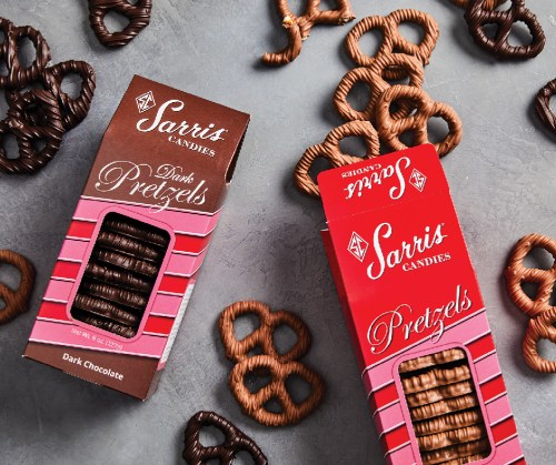 Two boxes of Sarris Candies pretzels, one dark chocolate and one regular, surrounded by pretzel shapes on a gray background.