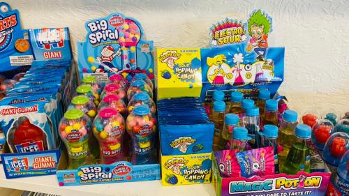 Colorful candy display featuring various sweets like gumballs, sour popping candy, and magic potion drinks.
