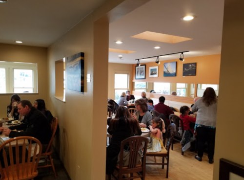 A cozy restaurant interior with diners at wooden tables, enjoying meals in a warm, inviting atmosphere.