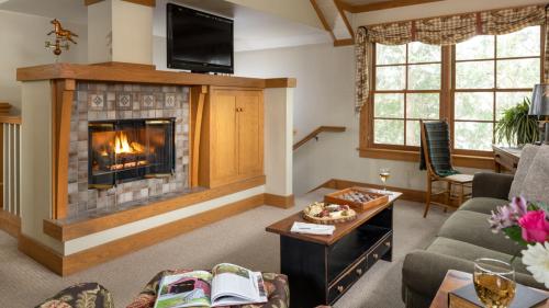 Cozy living room with a fireplace, TV, and a coffee table set with snacks and drinks, surrounded by large windows.