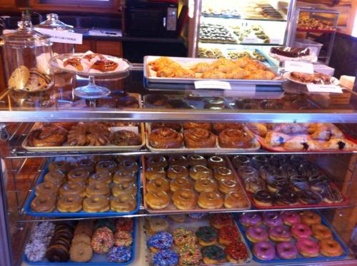 A display case filled with various donuts, pastries, and cookies in a bakery.