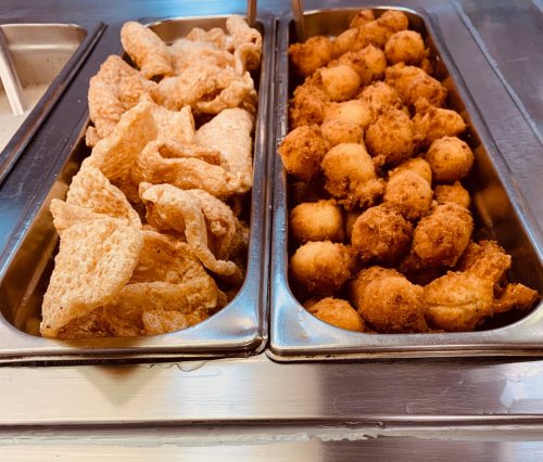 Two trays of fried snacks: one with crispy pork rinds and the other with golden-brown hush puppies.