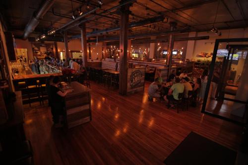A spacious restaurant interior with wooden floors, bar seating, and patrons enjoying their meals and drinks.