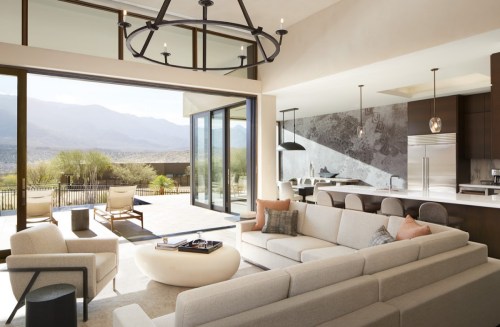 Modern living room with large windows, mountain views, and a sleek kitchen in an open-concept design.