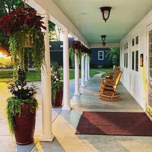A serene porch with rocking chairs, hanging plants, and a warm sunset glow illuminating the space.