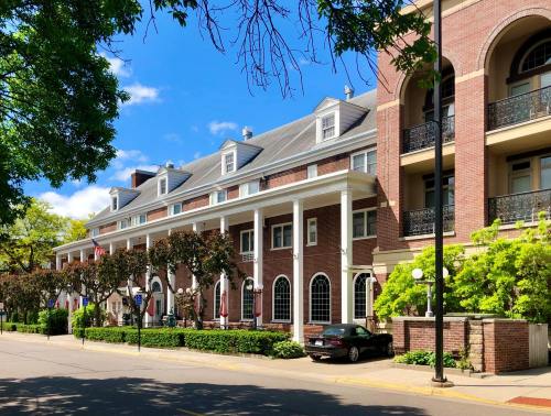A row of elegant brick buildings with white columns, surrounded by greenery and a clear blue sky.