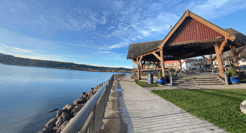 A waterfront view featuring a gazebo, pathway, and calm water under a clear blue sky.