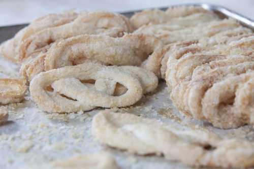 A close-up of freshly made, sugar-coated pastries arranged on a baking sheet.