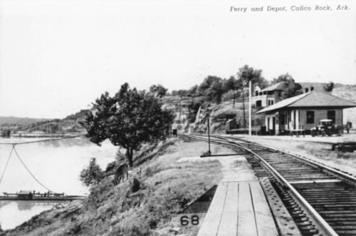 Black and white photo of a ferry and depot by a river in Calico Rock, Arkansas, with train tracks nearby.