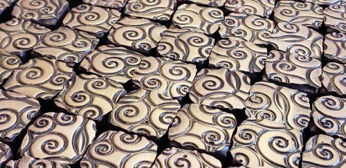 A close-up of intricately designed metallic tiles featuring swirling patterns.