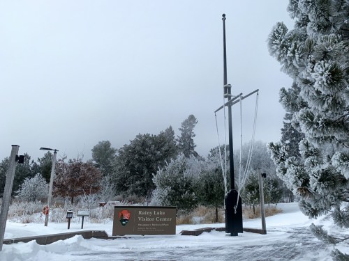 Sign for Rainy Lake Visitor Center surrounded by snow-covered trees and a frosty landscape.