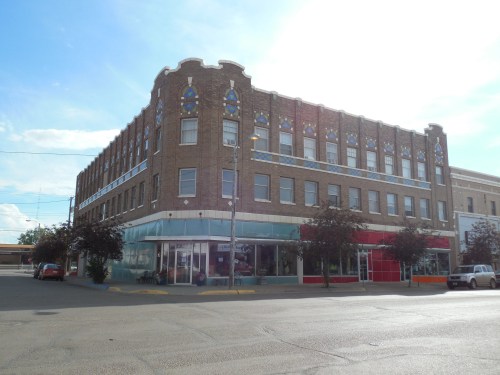 Historic brick building with decorative elements, featuring large windows and storefronts on the ground floor.