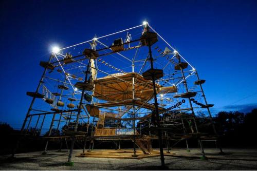 A large, illuminated climbing structure with various levels and obstacles, set against a night sky.