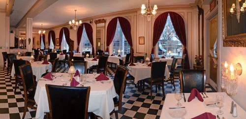 Elegant restaurant interior with checkered floor, white tablecloths, and red curtains, featuring tables set for dining.