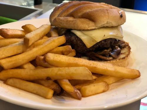 A juicy cheeseburger with melted cheese and sautéed onions, served with a side of golden French fries.