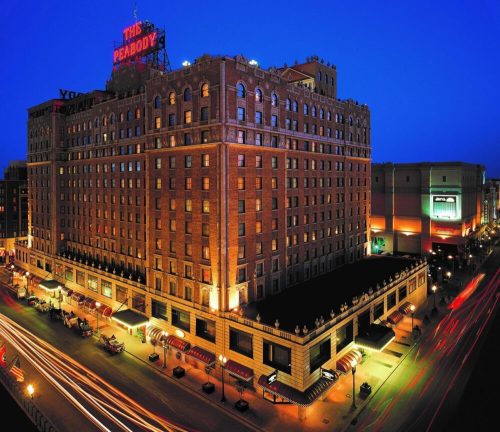 The Peabody Hotel illuminated at night, showcasing its historic architecture and vibrant city surroundings.
