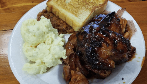 A plate with grilled chicken, mashed potatoes, baked beans, and a slice of toasted bread.