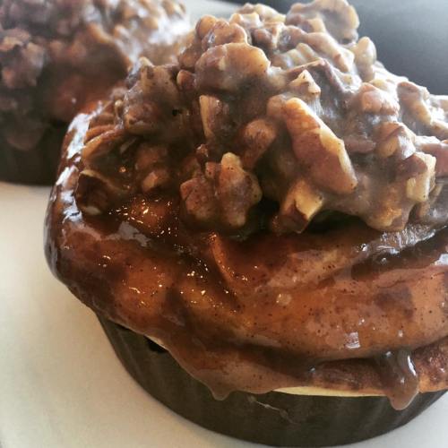 Close-up of a cupcake topped with a rich, caramel-like frosting and crunchy pecans.