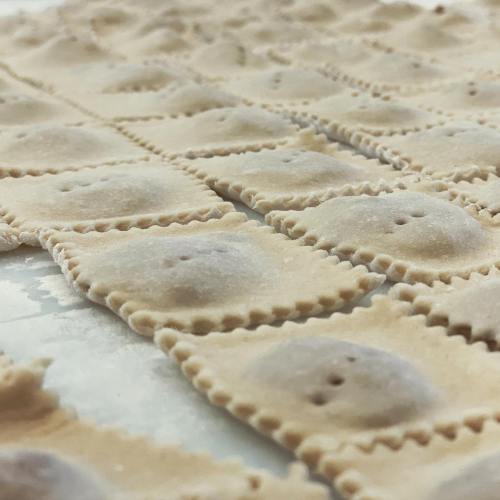 Close-up of uncooked pasta sheets with a textured surface, arranged neatly on a flat surface.