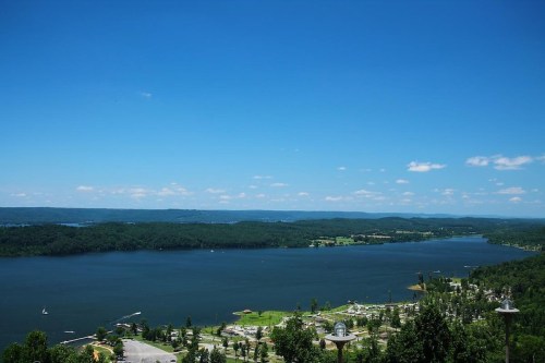 A scenic view of a river surrounded by green hills under a clear blue sky, with boats on the water.
