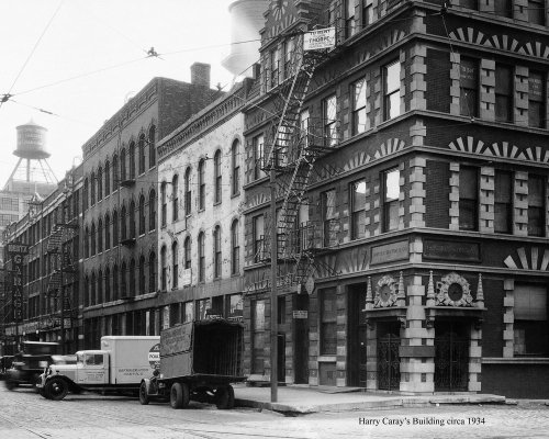 Historic black-and-white photo of Harry Caray's Building, featuring a fire escape and vintage vehicles, circa 1934.