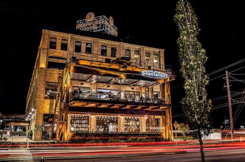 A historic building at night, illuminated with warm lights, featuring a restaurant and outdoor seating area.