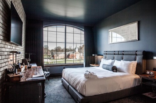 Modern hotel room featuring a large bed, stylish decor, and a window with a view of the outdoors.