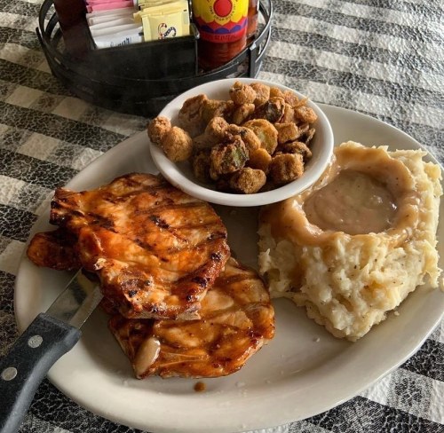 Grilled chicken with mashed potatoes and gravy, served with a side of fried okra on a checkered tablecloth.
