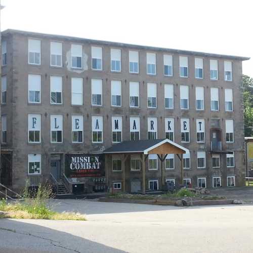 A large building with "FLEA MARKET" sign on the front, featuring multiple windows and a small entrance.