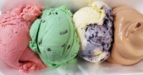 A container with four scoops of colorful ice cream: pink, green, yellow, and brown.