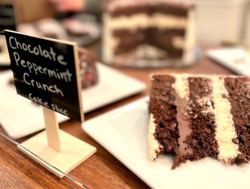 A slice of chocolate peppermint crunch cake on a plate, with a small sign indicating the cake's name.