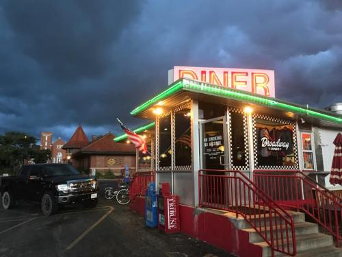 A retro diner with neon lights, an American flag, and a dark, stormy sky in the background.
