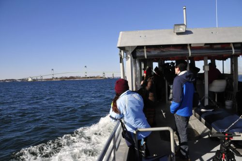 Passengers on a boat enjoy a scenic view of a bridge over water on a clear day.