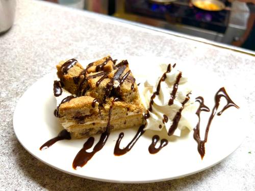 A plate with chocolate-drizzled dessert squares and a dollop of whipped cream.