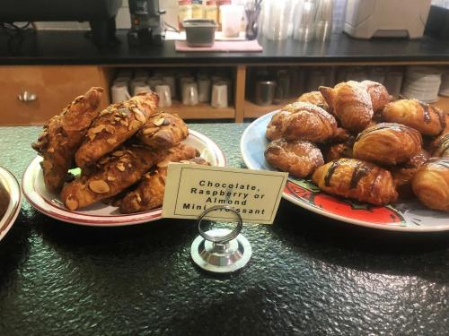 A display of mini croissants: almond, chocolate, and raspberry varieties on plates with a sign.