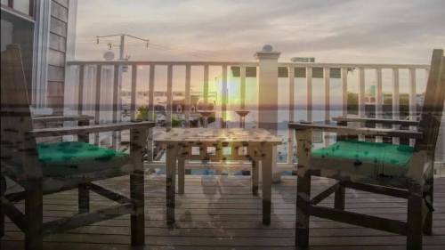 A balcony with two chairs overlooks a sunset over the water, creating a serene and inviting atmosphere.