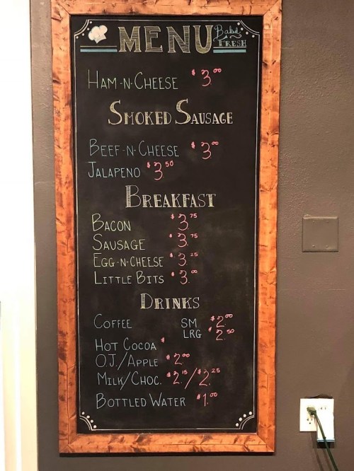 Chalkboard menu listing food items and prices: ham & cheese, smoked sausage, breakfast options, and drinks.