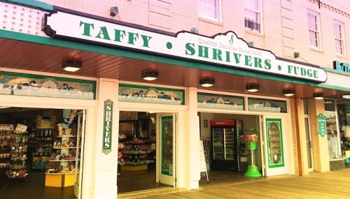 Storefront of Shrivers, featuring signs for taffy and fudge, with colorful displays and a welcoming entrance.