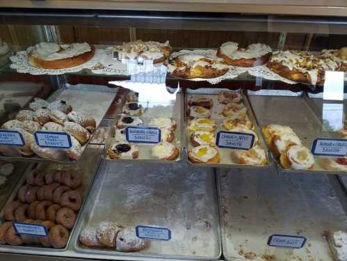 A display case filled with various pastries, including danishes and donuts, labeled with their names.