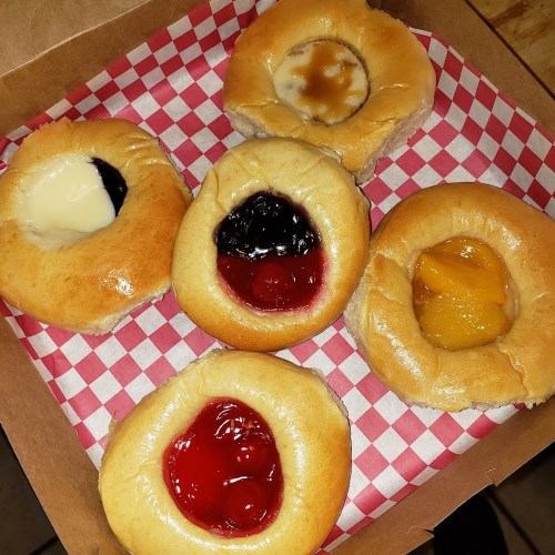 A box of five sweet pastries with various fruit fillings: cherry, blueberry, peach, and cream.