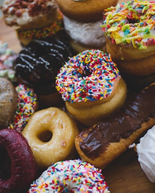 A colorful assortment of donuts with various toppings, including sprinkles, chocolate, and fruity decorations.