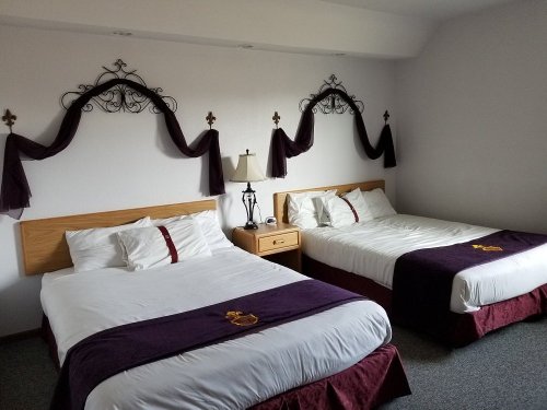 A cozy hotel room with two beds, decorative wall accents, and a lamp on a nightstand.