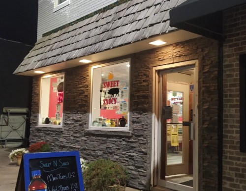 Exterior of "Sweet N Saucy" restaurant at night, featuring a stone facade and illuminated windows.