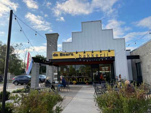 Exterior of de Boer's Bakkerij, a bakery with outdoor seating, string lights, and a clear blue sky.